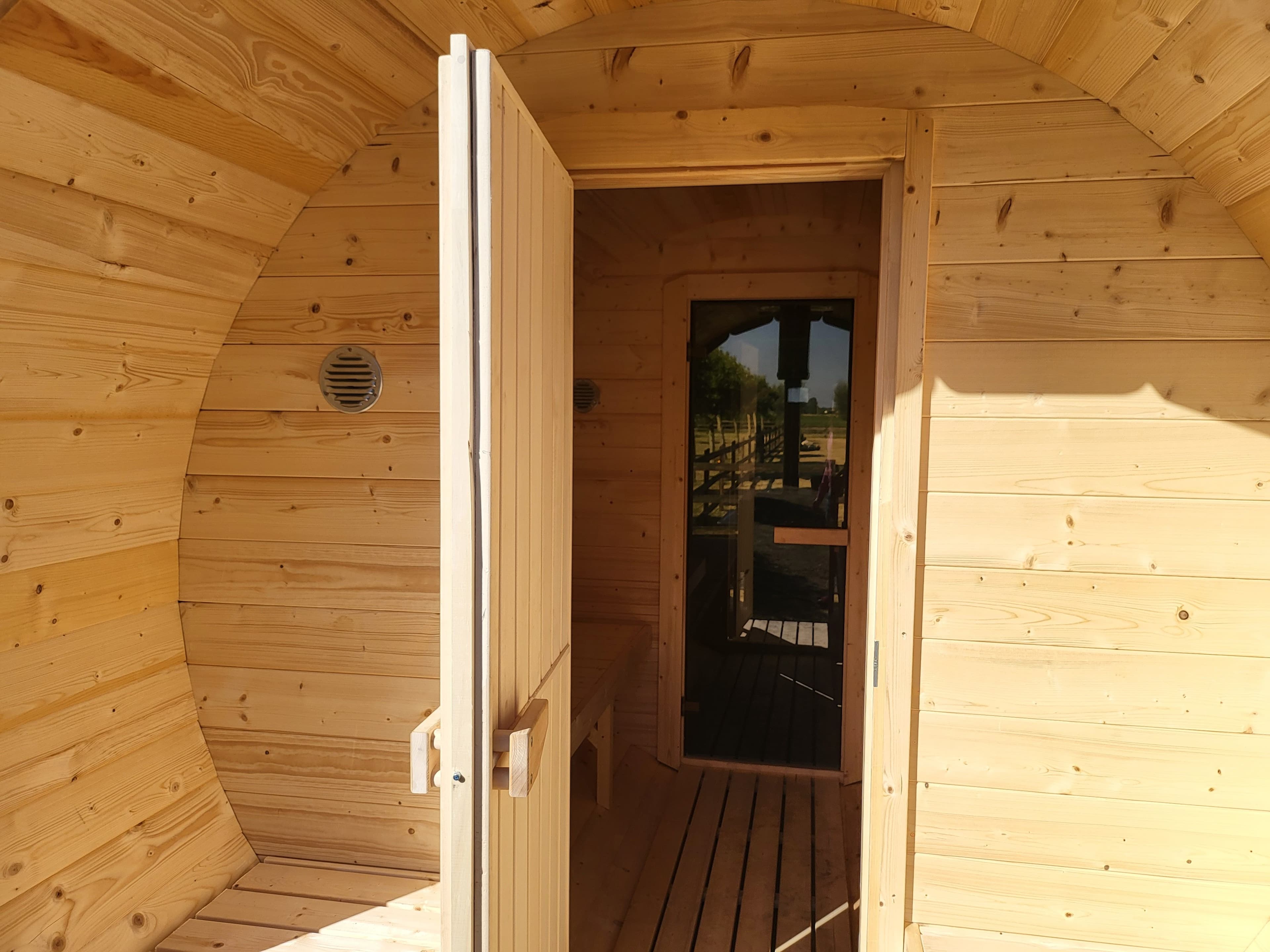 Modern round wooden barrel sauna with glass
