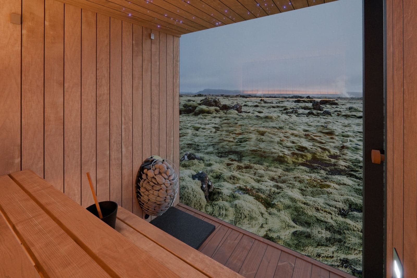 Vista dall'interno della sauna: panche in pioppo tremulo, stufa rotonda con pietre, soffitto a cielo stellato e parete di vetro su un paesaggio vulcanico coperto di muschio