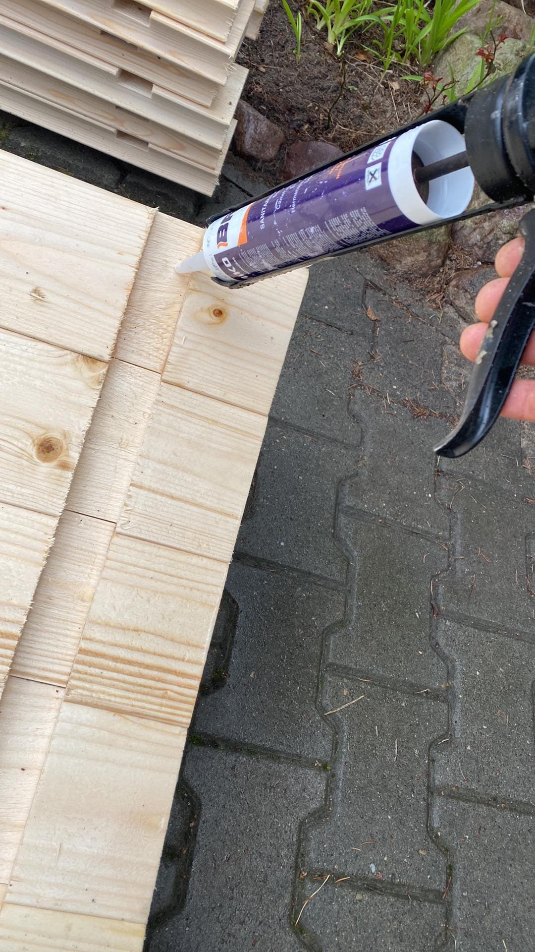 Fogpistol som lägger silikonfogmassa i spåret som skurits tvärs över basens stavar